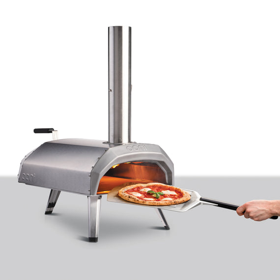 Pizza oven with someone inserting a pizze using a pizza peel